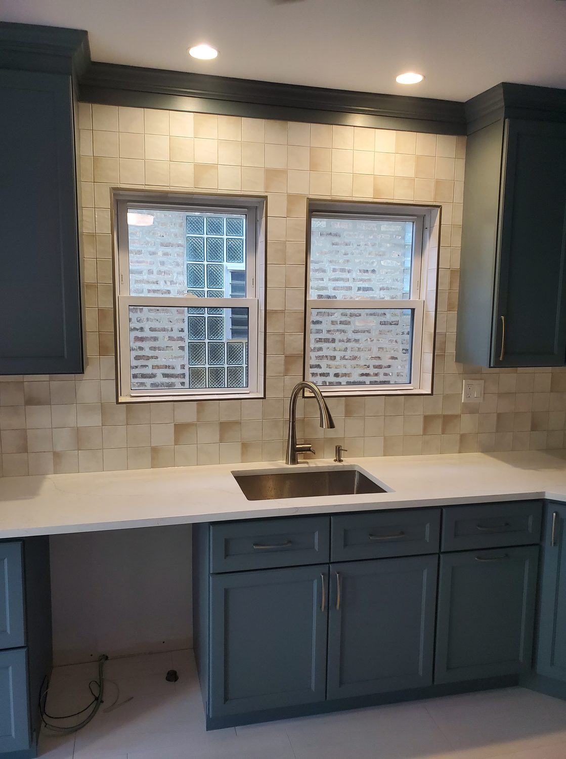 Kitchen with teal cabinetry, tile backsplash, and quartz countertops
